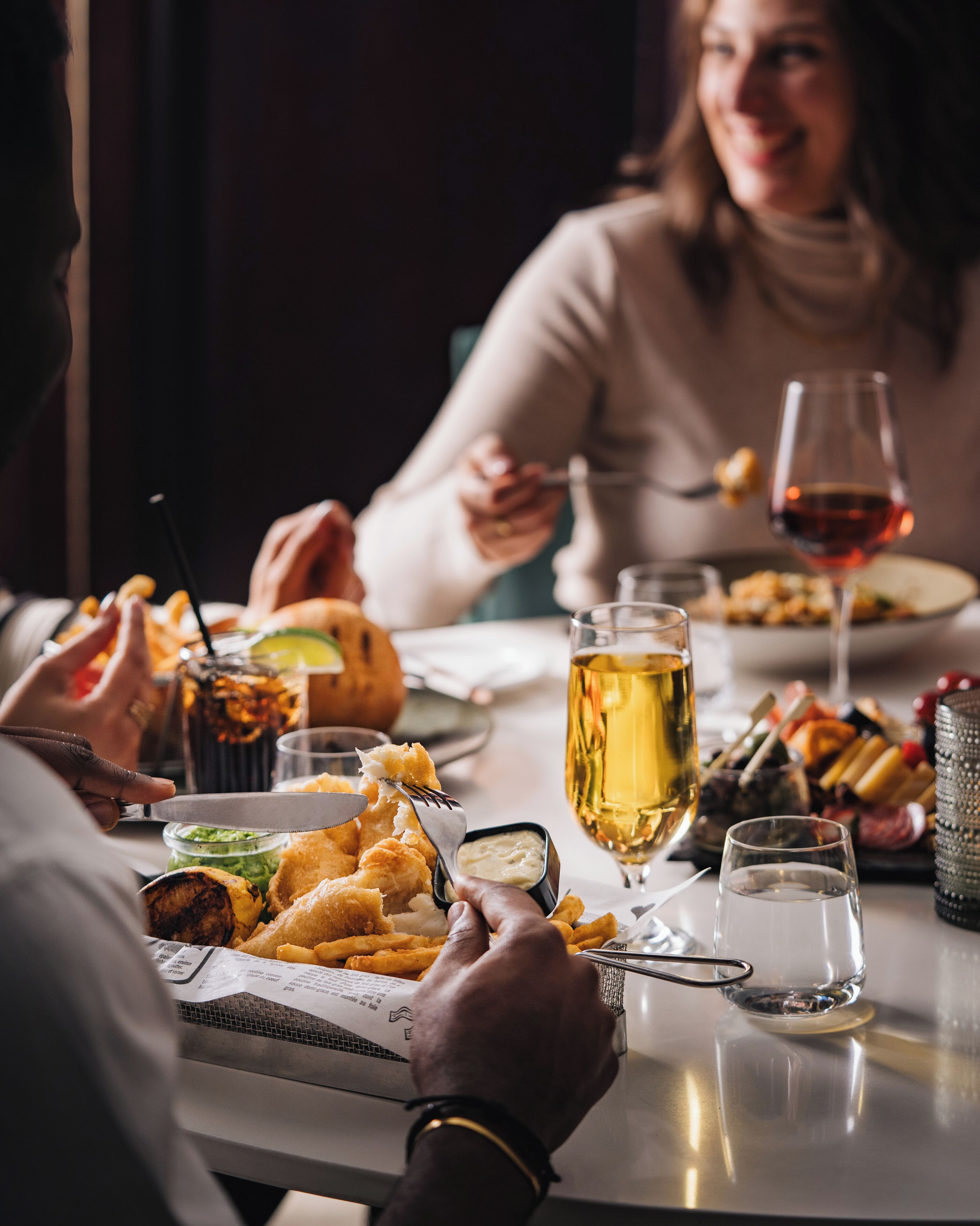 A dining table with various dishes, including fried items and a glass of wine, suggesting a restaurant setting.