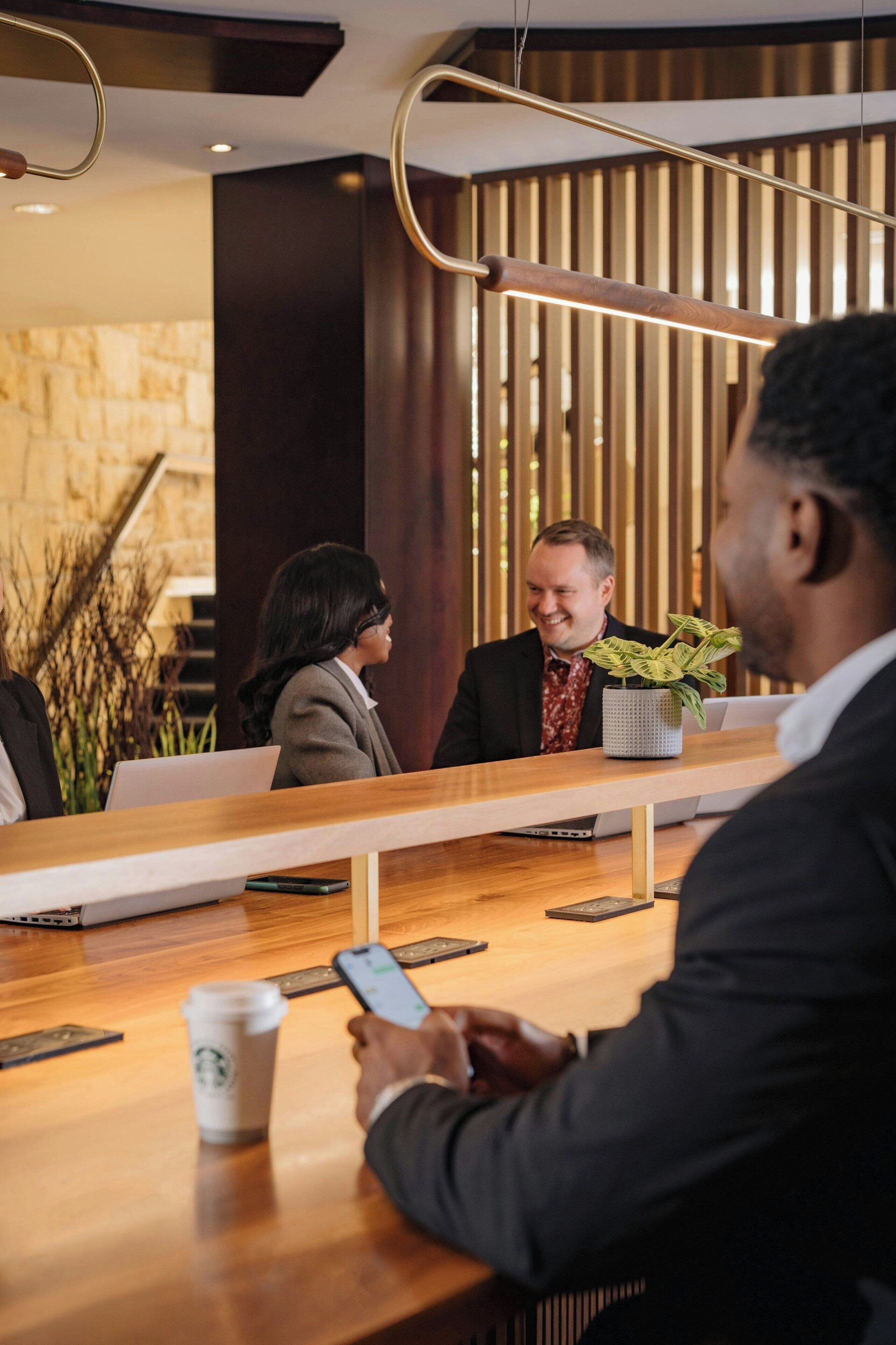 A reception area with a wooden reception desk, a laptop, a smartphone, and a Starbucks cup.