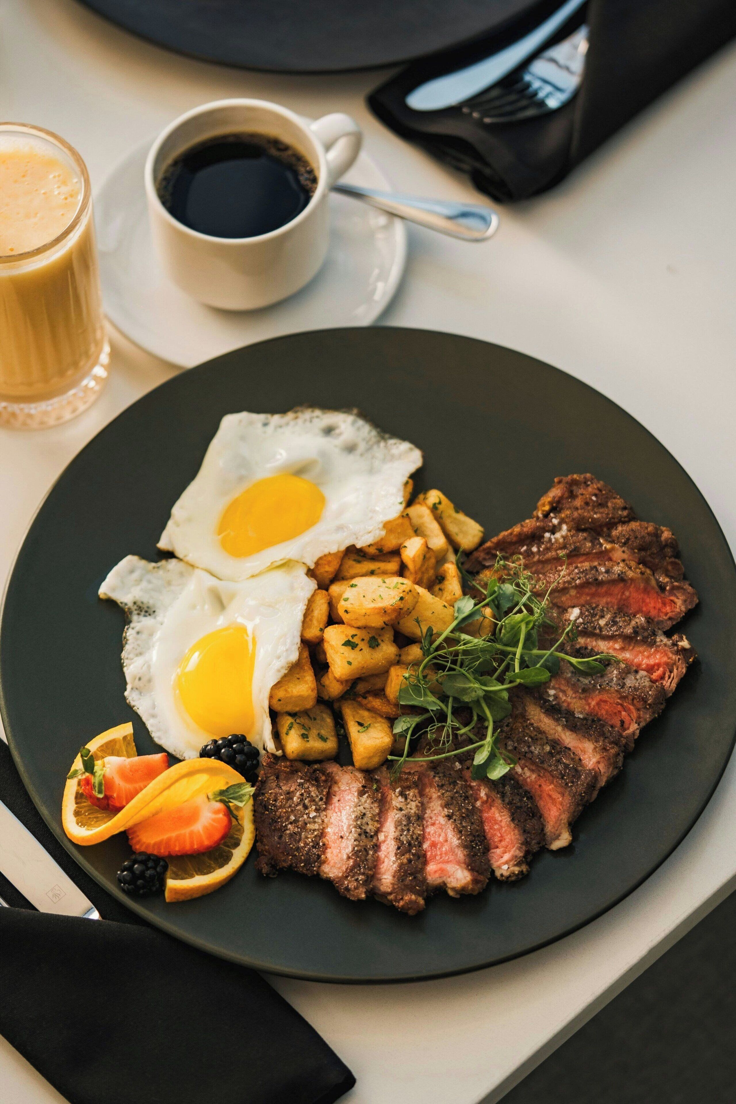 Un plato con bistec, huevos fritos y papas.