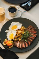 Un plato con bistec, huevos fritos y papas.