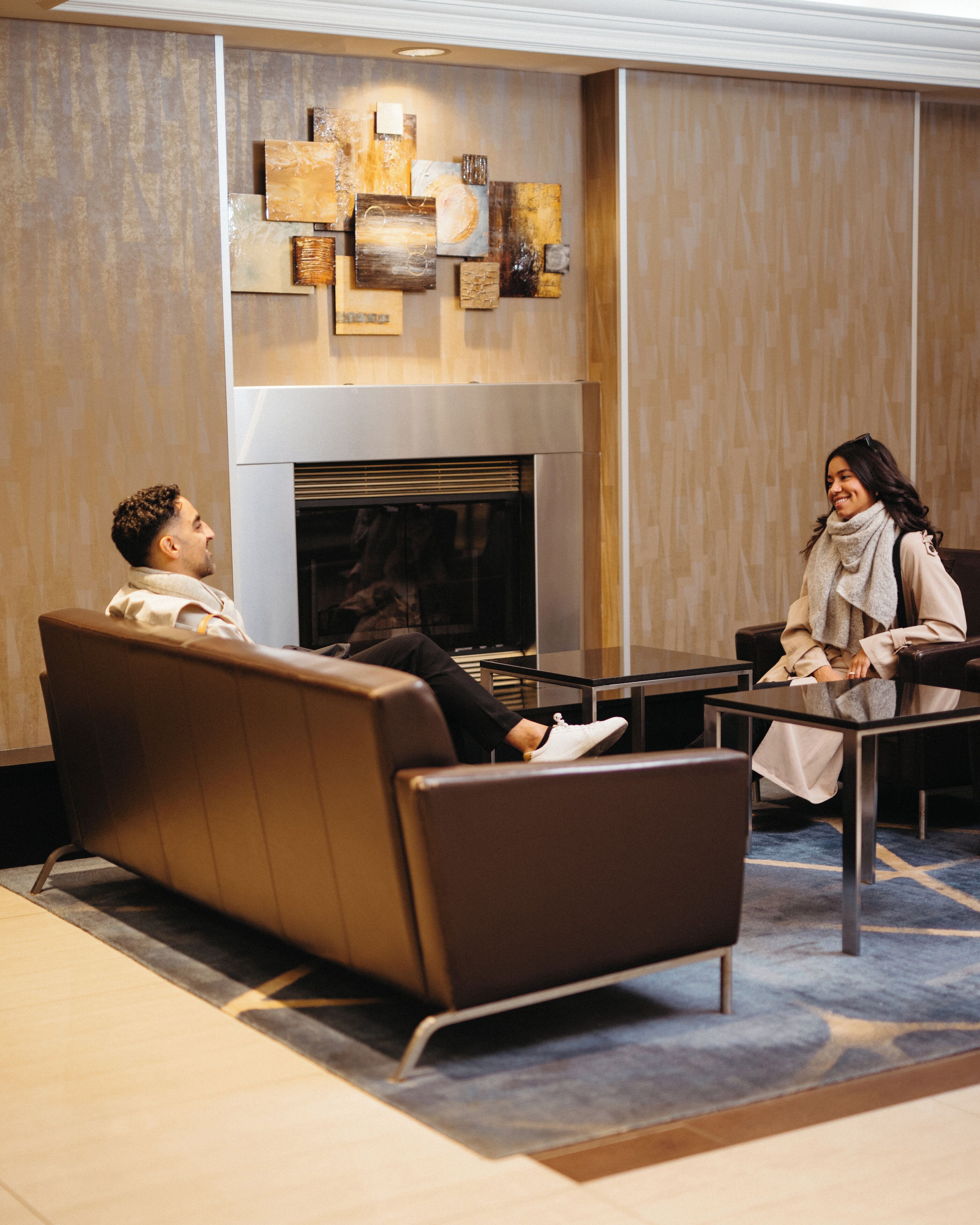 A modern lobby with a fireplace, leather seating, and abstract wall art.