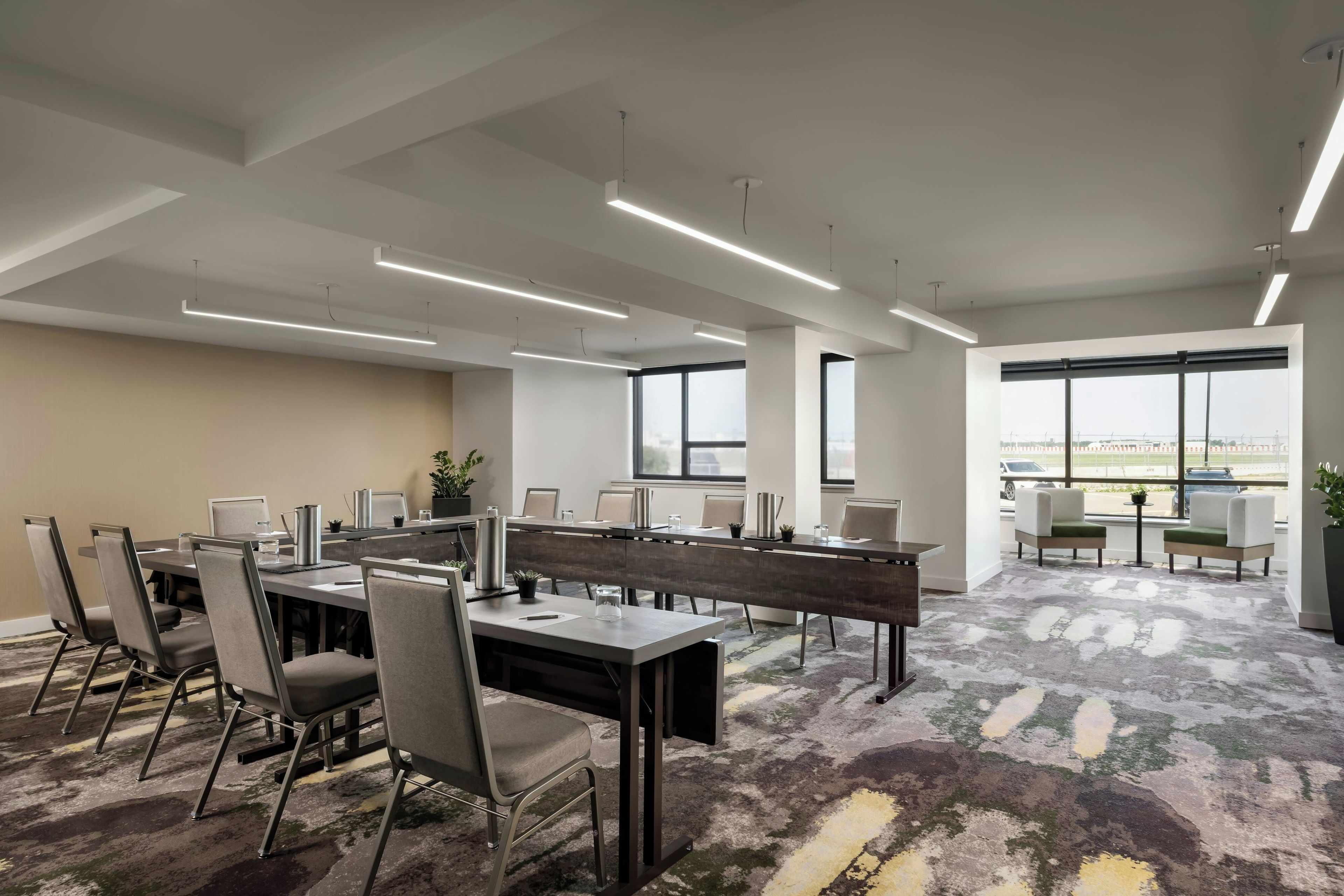 Un espace de bureau moderne doté de plusieurs postes de travail, de chaises et de tables.