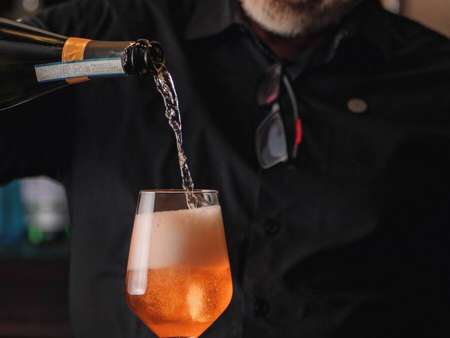 Um bartender servindo uma bebida em taça.