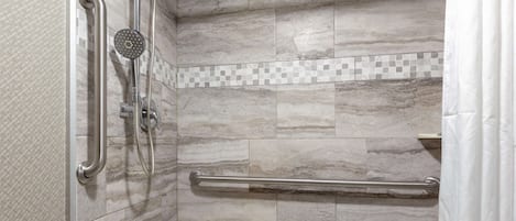 A shower area with a handrail, a showerhead, and a tiled wall.