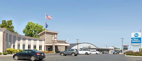 A Best Western hotel with a parking lot, a flag, and a building with a curved roof.