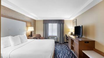Hotelkamer met een groot bed, een bureau met een televisie, een stoel en een raam met gordijnen.
