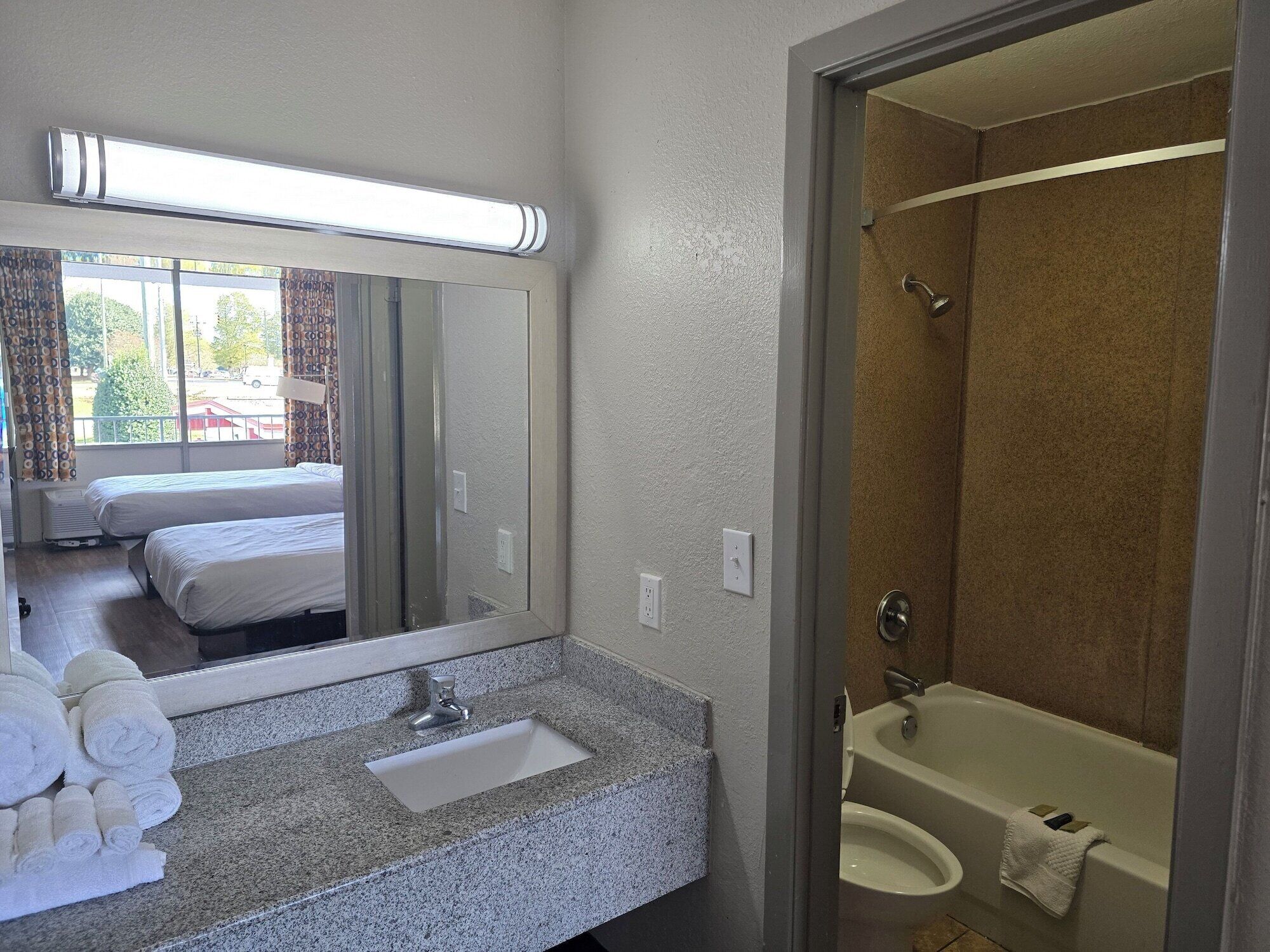 A hotel bathroom with a sink, mirror, and shower.