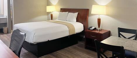 A hotel room with a bed, bedside tables, a desk, and a chair.