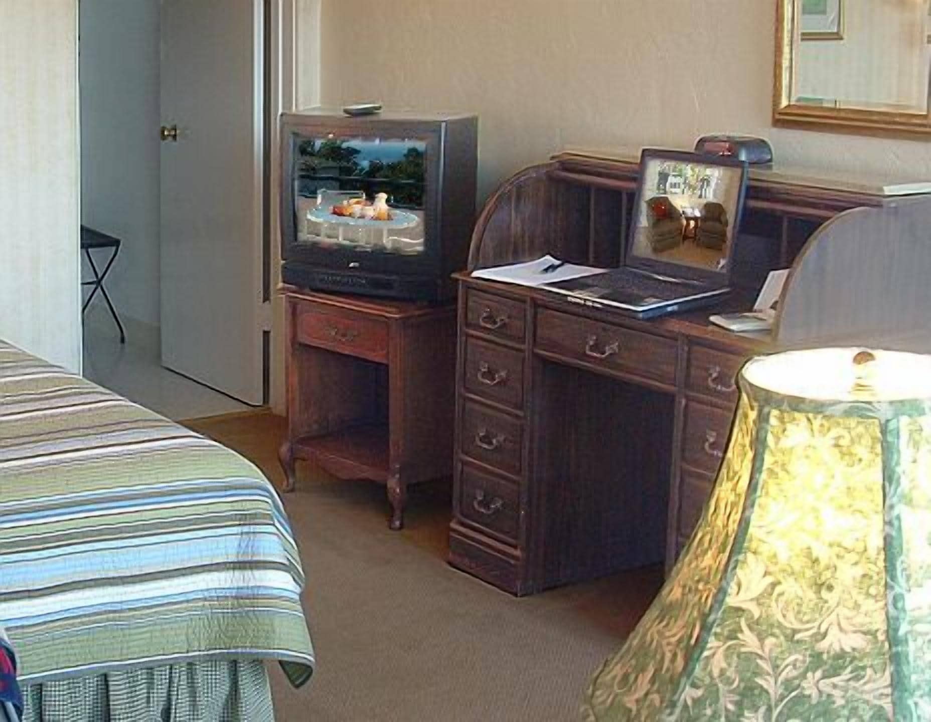 Une chambre d’hôtel avec un lit, un bureau en bois doté de tiroirs, une télévision et une lampe.