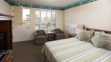 A hotel room with a bed, a television, a desk, and a window with blinds.