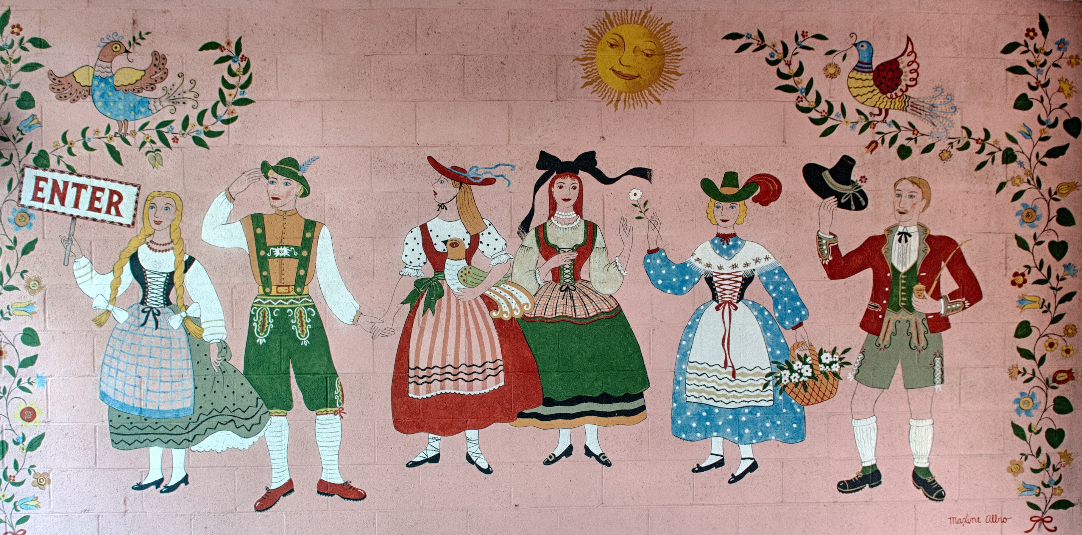 Ein Wandgemälde mit Figuren in traditioneller Tracht, einem 'ENTER'-Schild sowie dekorativen Vögeln und einer Sonne.
