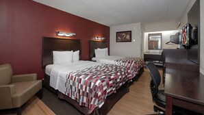 Ein Hotelzimmer mit zwei Betten, einem Schreibtisch, einem Stuhl und einem Fernseher.