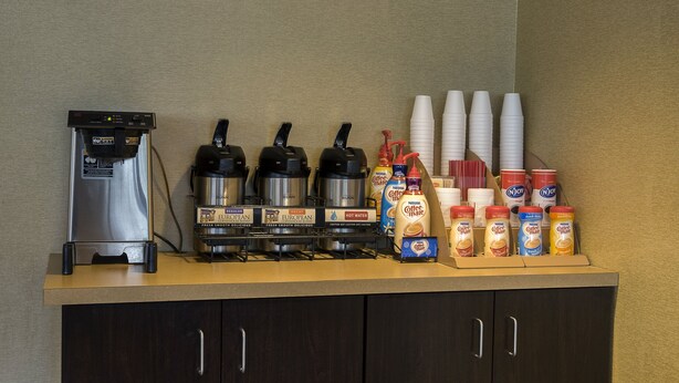 Eine Kaffeestation mit Kaffeemaschine, Wasserkochern, Tassen und Sahnespendern.