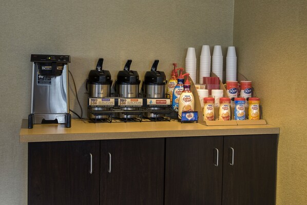 A coffee station with a coffee maker, kettles, cups, and coffee creamer dispensers. - Red Roof Inn Washington DC - Lanham (Lanham)