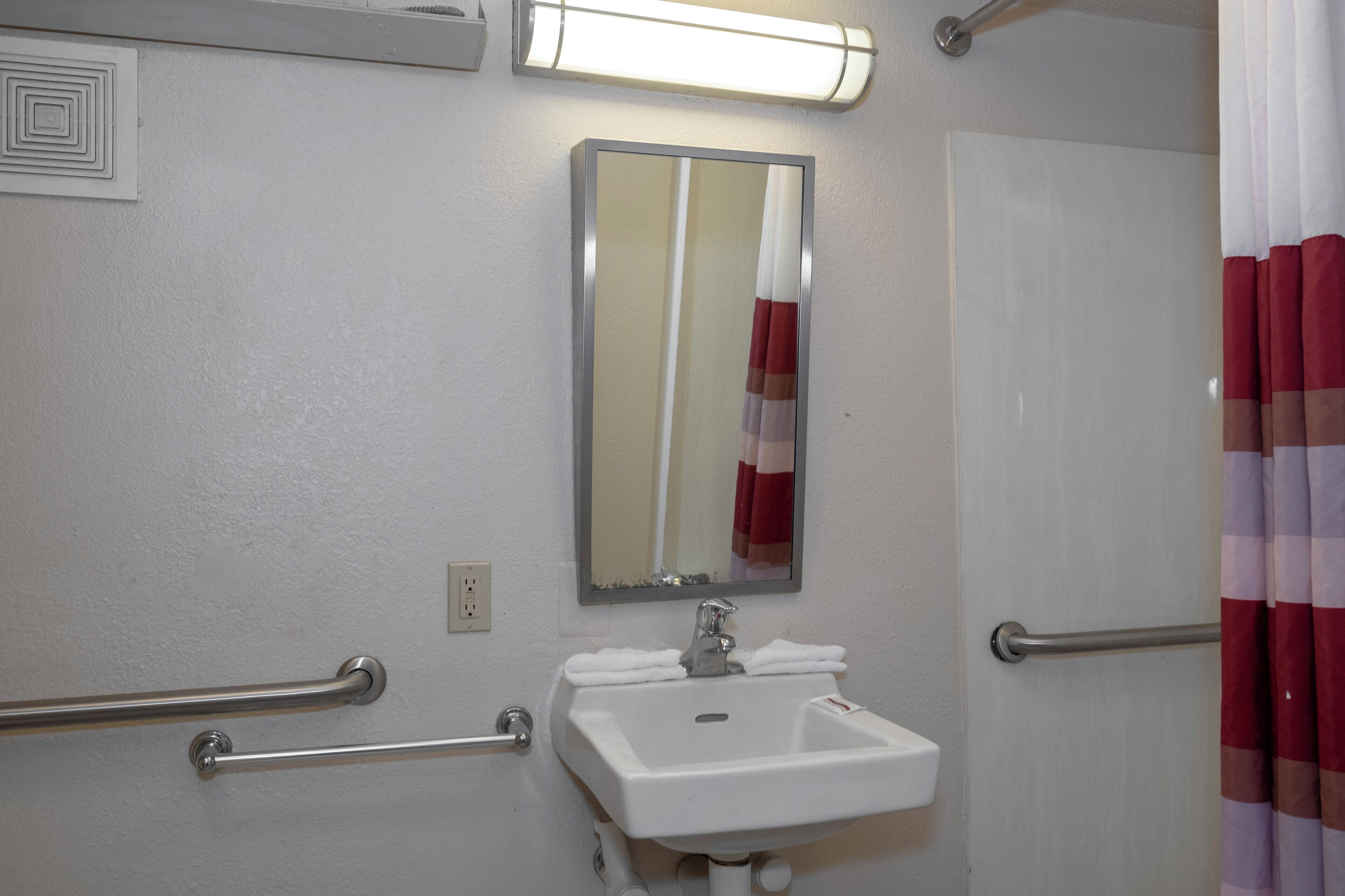 Une salle de bain avec un lavabo blanc, un miroir, un porte-serviettes et un rideau de douche.