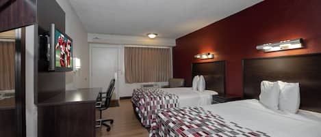 Habitación de hotel con dos camas, un escritorio, una silla, un televisor y una ventana con cortinas.