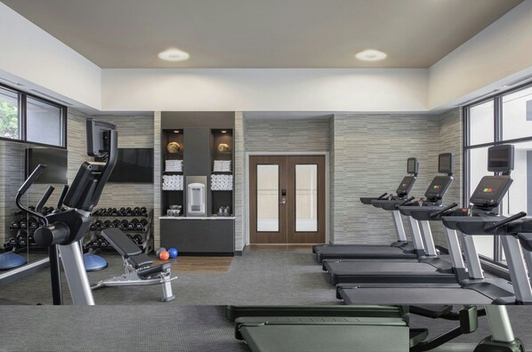 A gym with treadmills, dumbbells, and weight machines.