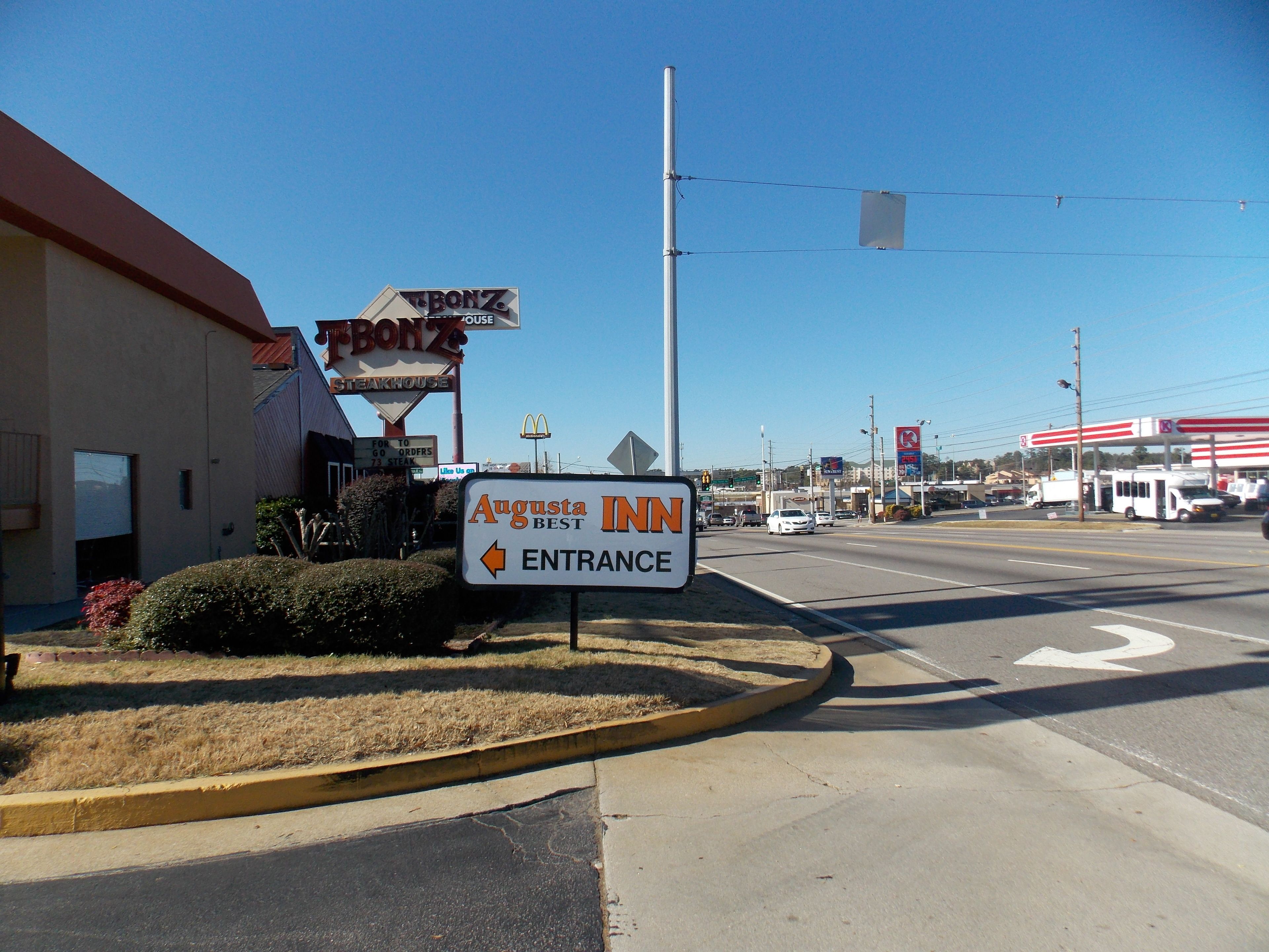 A sign for Augusta Inn with an entrance arrow, a McDonald's sign, and a 7-Eleven in the background.