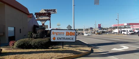 A sign for Augusta Inn with an entrance arrow, a McDonald's sign, and a 7-Eleven in the background.