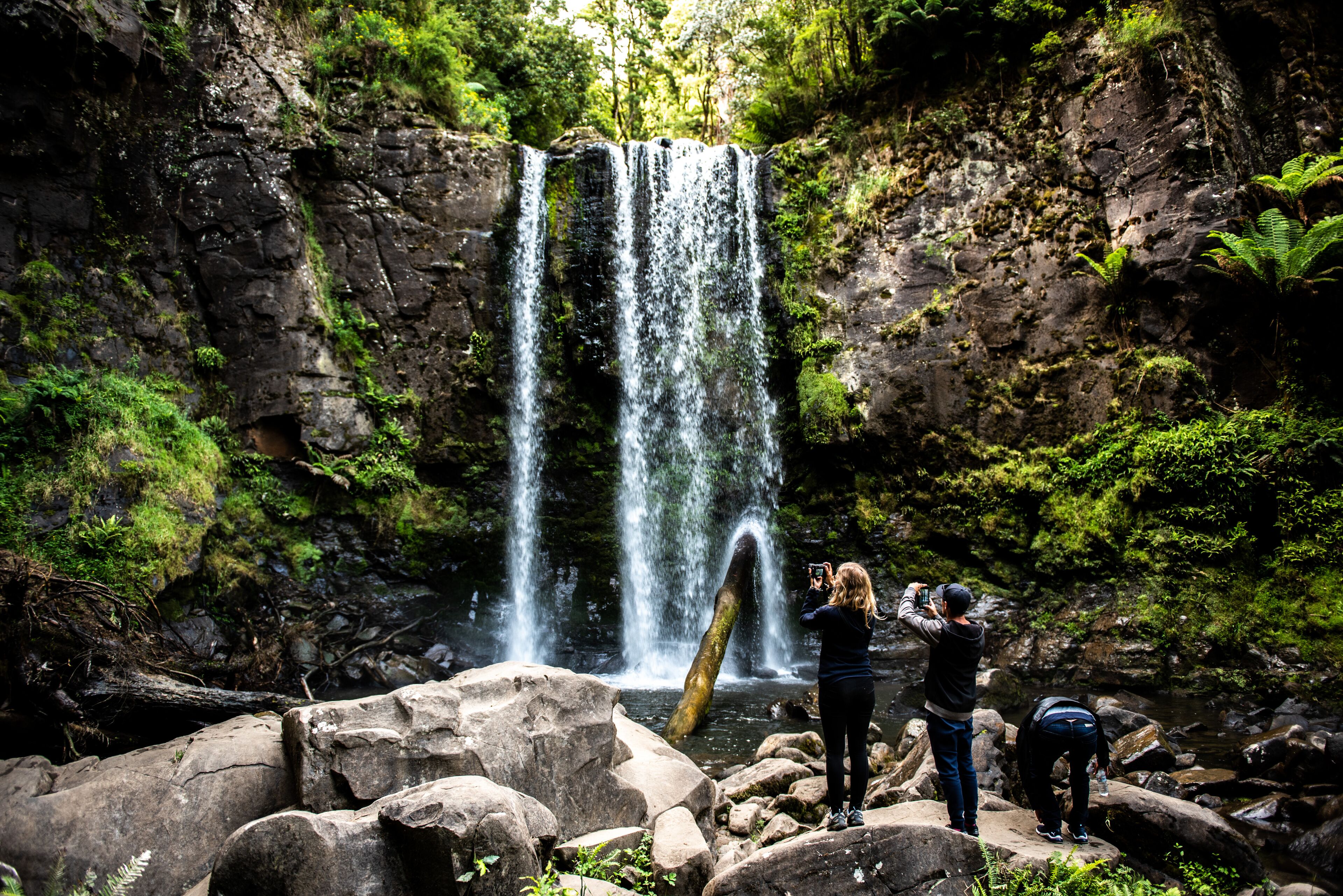 A waterfall surrounded by rocks and greenery.