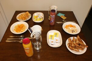 Una mesa de comedor con diversos alimentos para el desayuno, como tostadas, huevos revueltos y cereal.