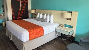 A hotel room with a bed, bedside lamps, a desk with a telephone, and a chair.