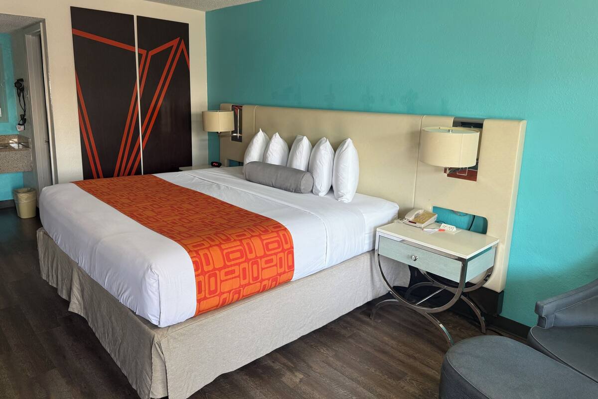 Een hotelkamer met een bed, bedlampen, een bureau met telefoon en een stoel.