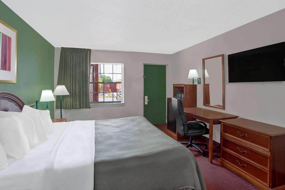 Een hotelkamer met een bed, bureau, stoel, dressoir en een televisie.