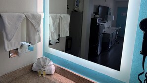 A bathroom with a large mirror, towels, a sink, and a hairdryer.