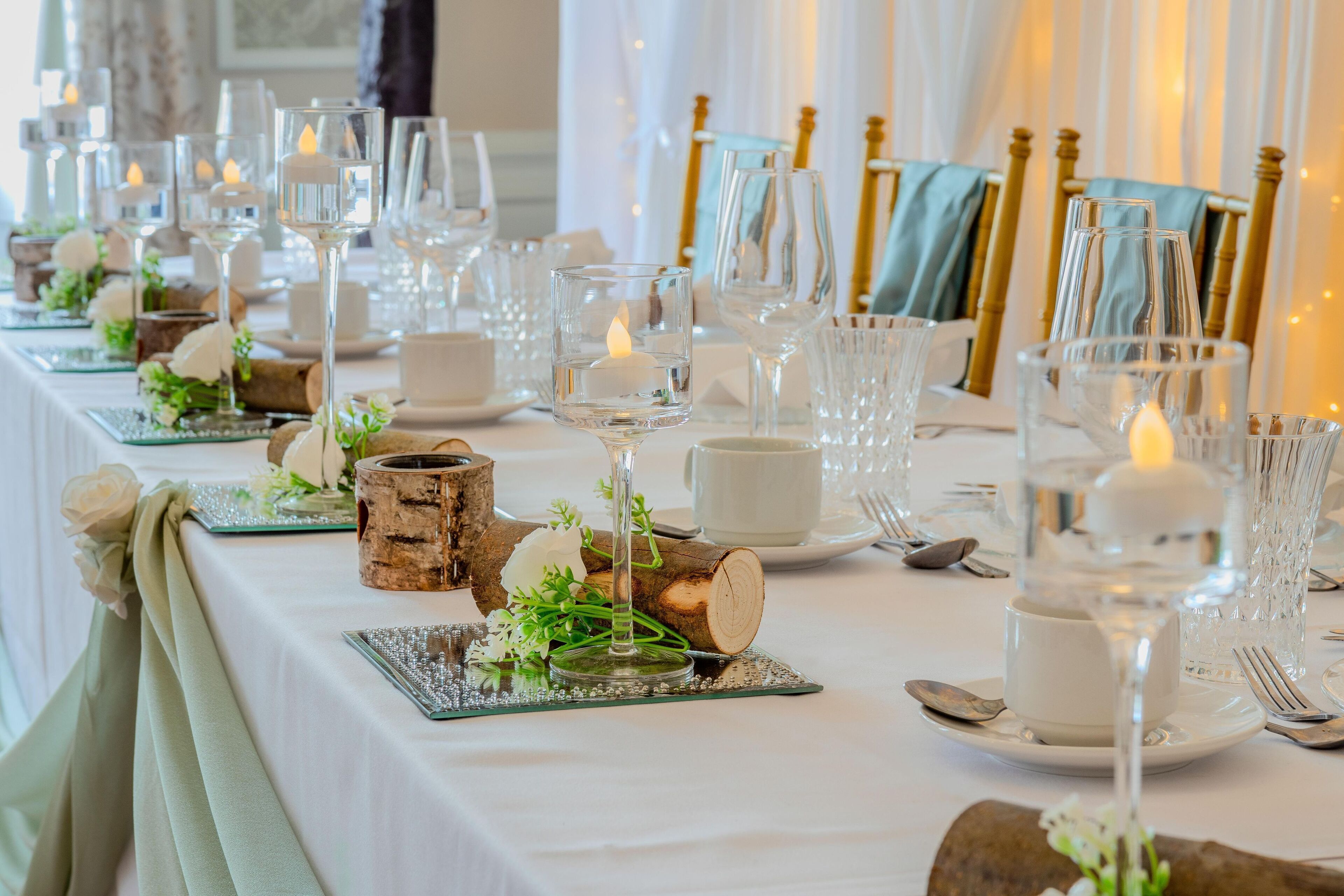 A table set with glassware, candles, and rustic decor elements.