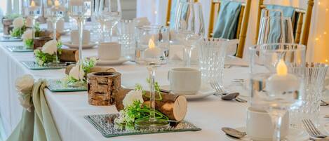 Una mesa dispuesta con cristalería, velas y elementos decorativos rústicos.