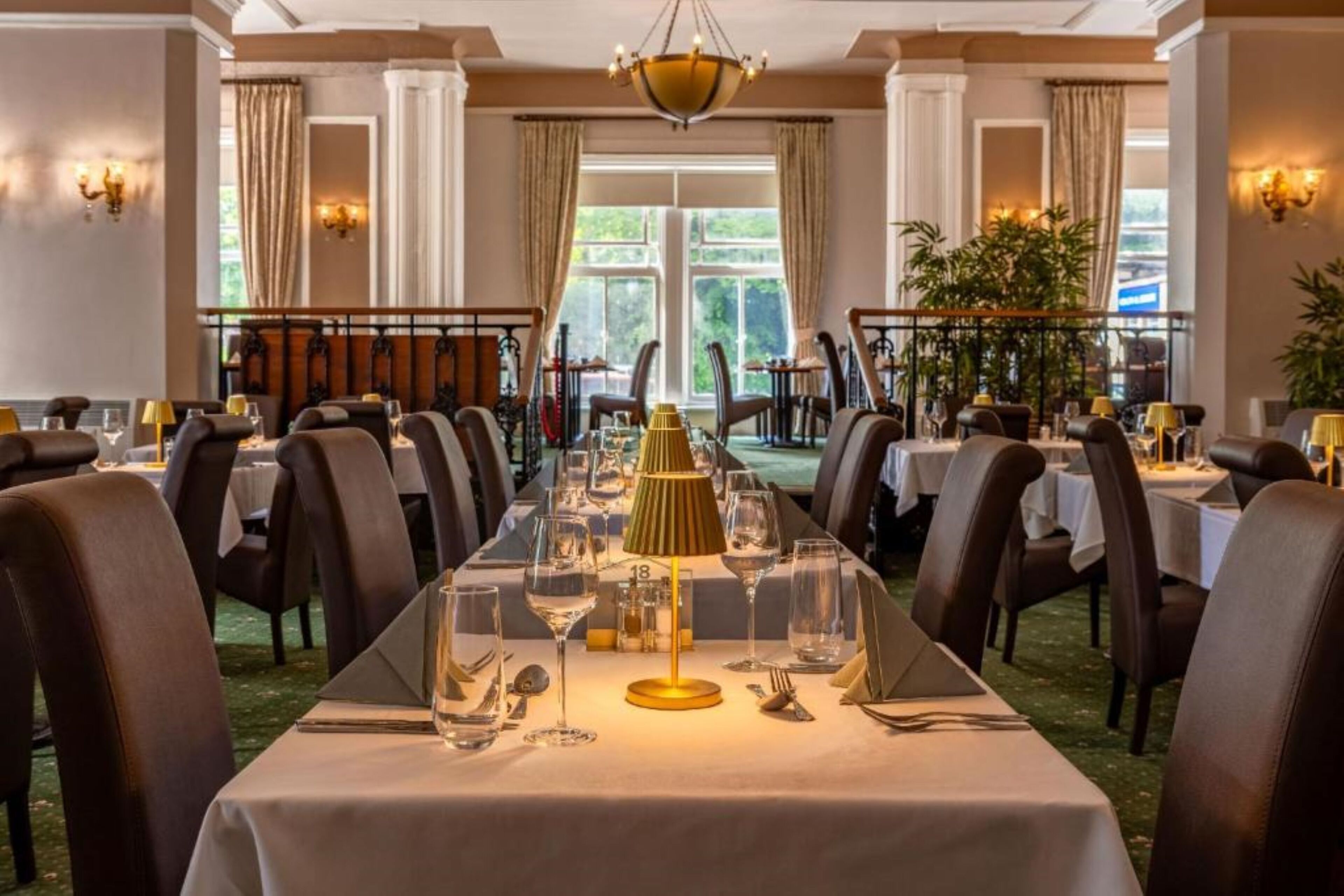 Une salle à manger élégante, avec une longue table dressée pour un repas, entourée de chaises.