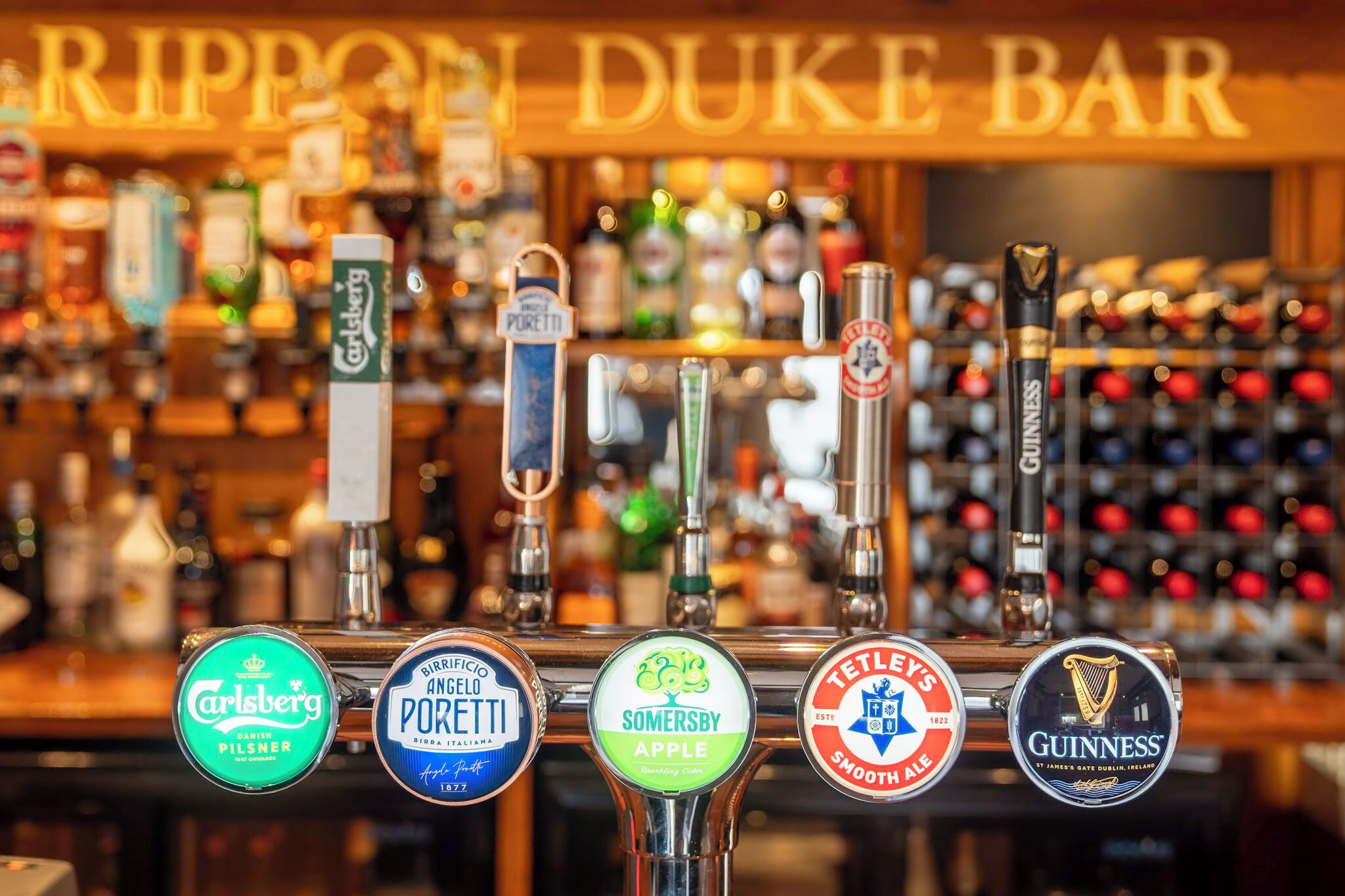 A bar with various beer taps including Carlsberg, Birrificio Andello Porretti, Somersby Apple, Tetley’s Smooth Ale, and Guinness.