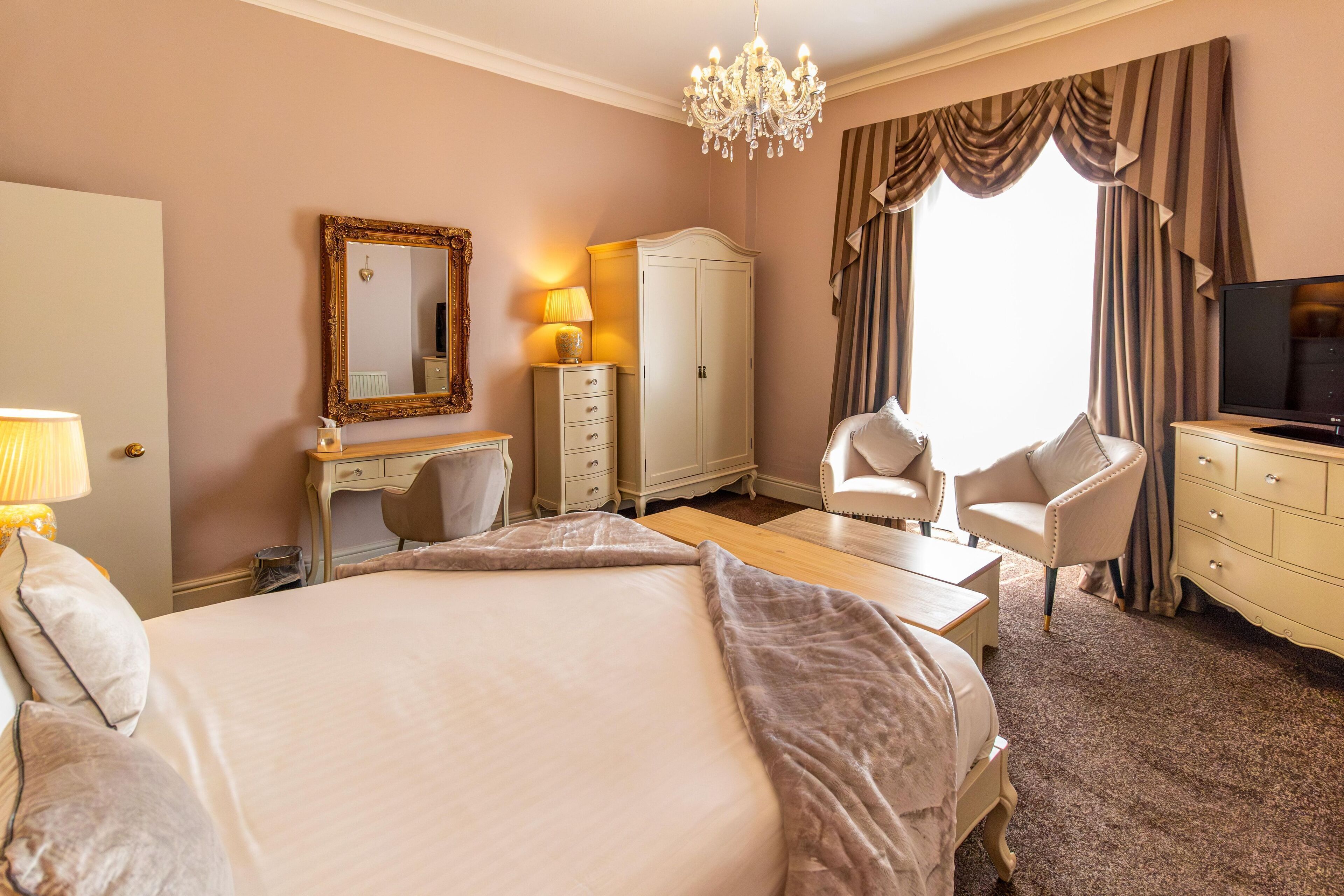 A hotel room with two beds, a desk, a chair, a television, and a wardrobe.