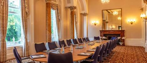 A conference room with a long table, chairs, and a fireplace.