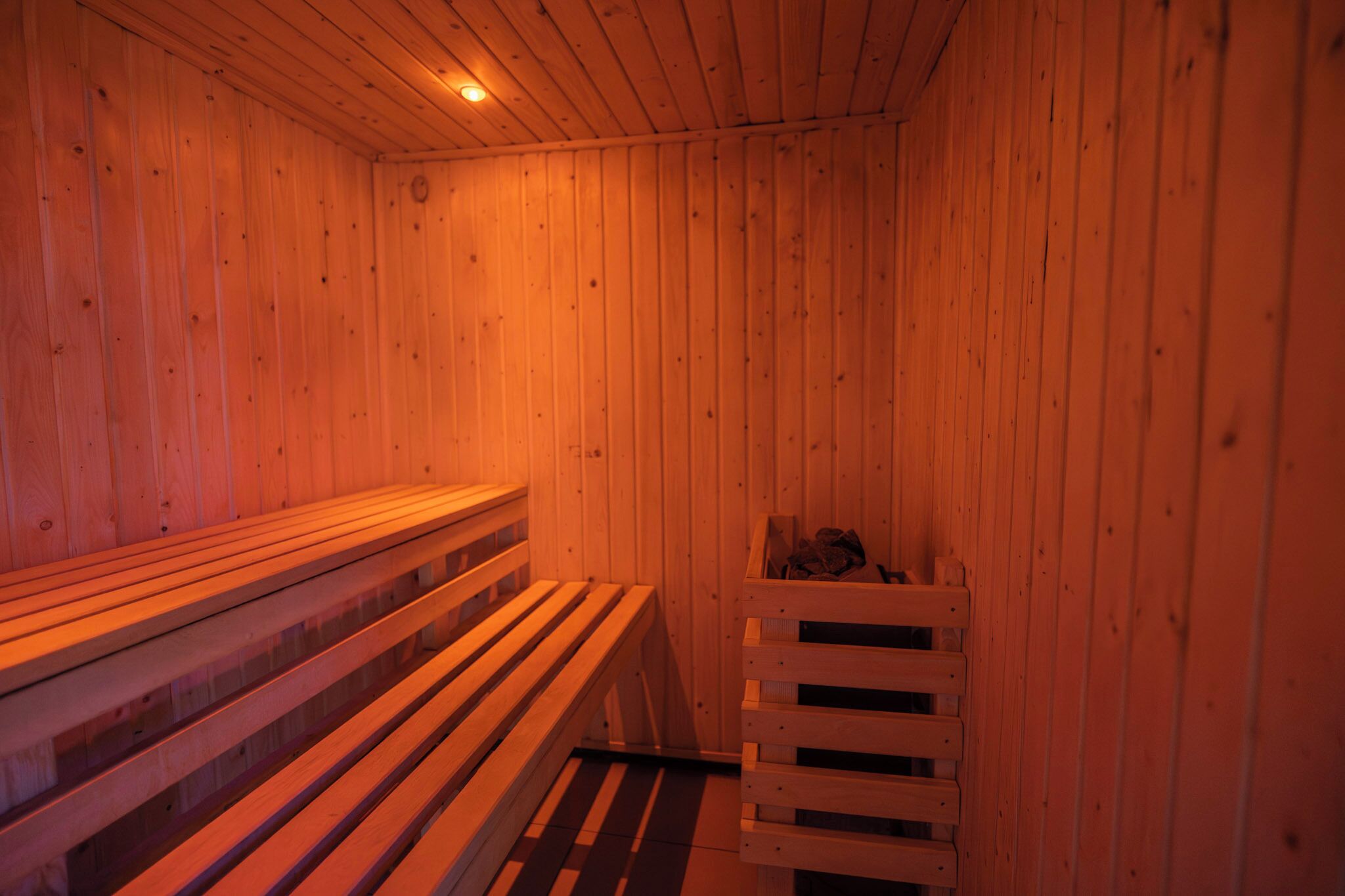 A wooden sauna with benches and a bench with a storage compartment.