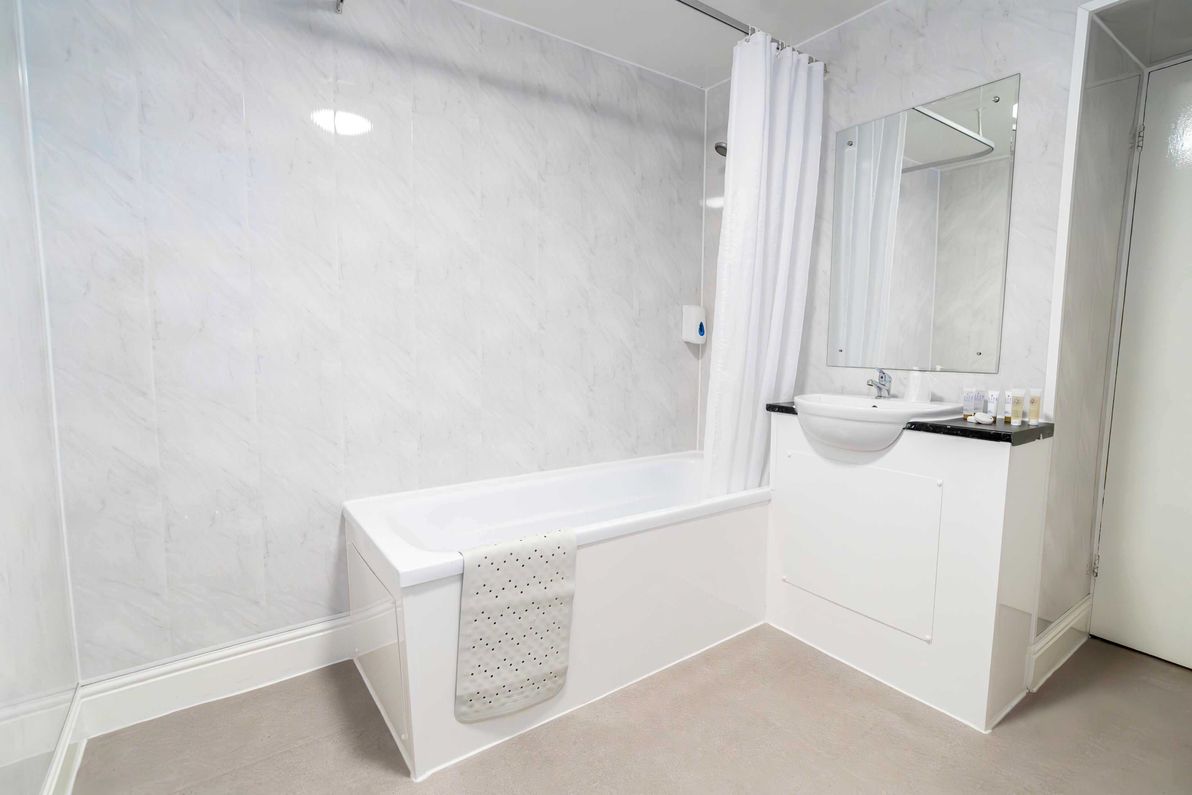 A modern bathroom with a white bathtub, a sink, and a mirror.