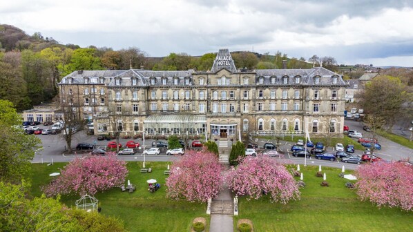 Stunning historic hotel with a traditional design, set amidst a lush green lawn and blooming trees.