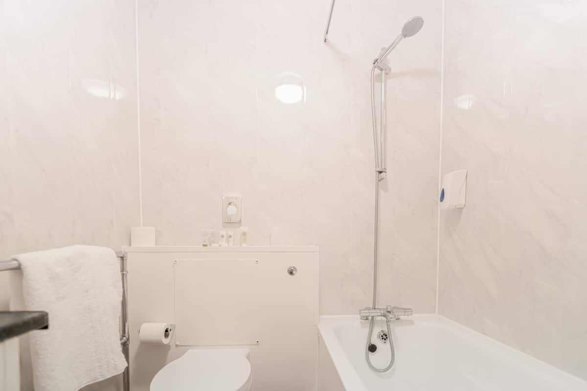 Ein Badezimmer mit Toilette, Handtuchhalter, Dusche und Badewanne.