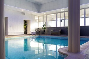 Una piscina techada, sillones reclinables de piscina