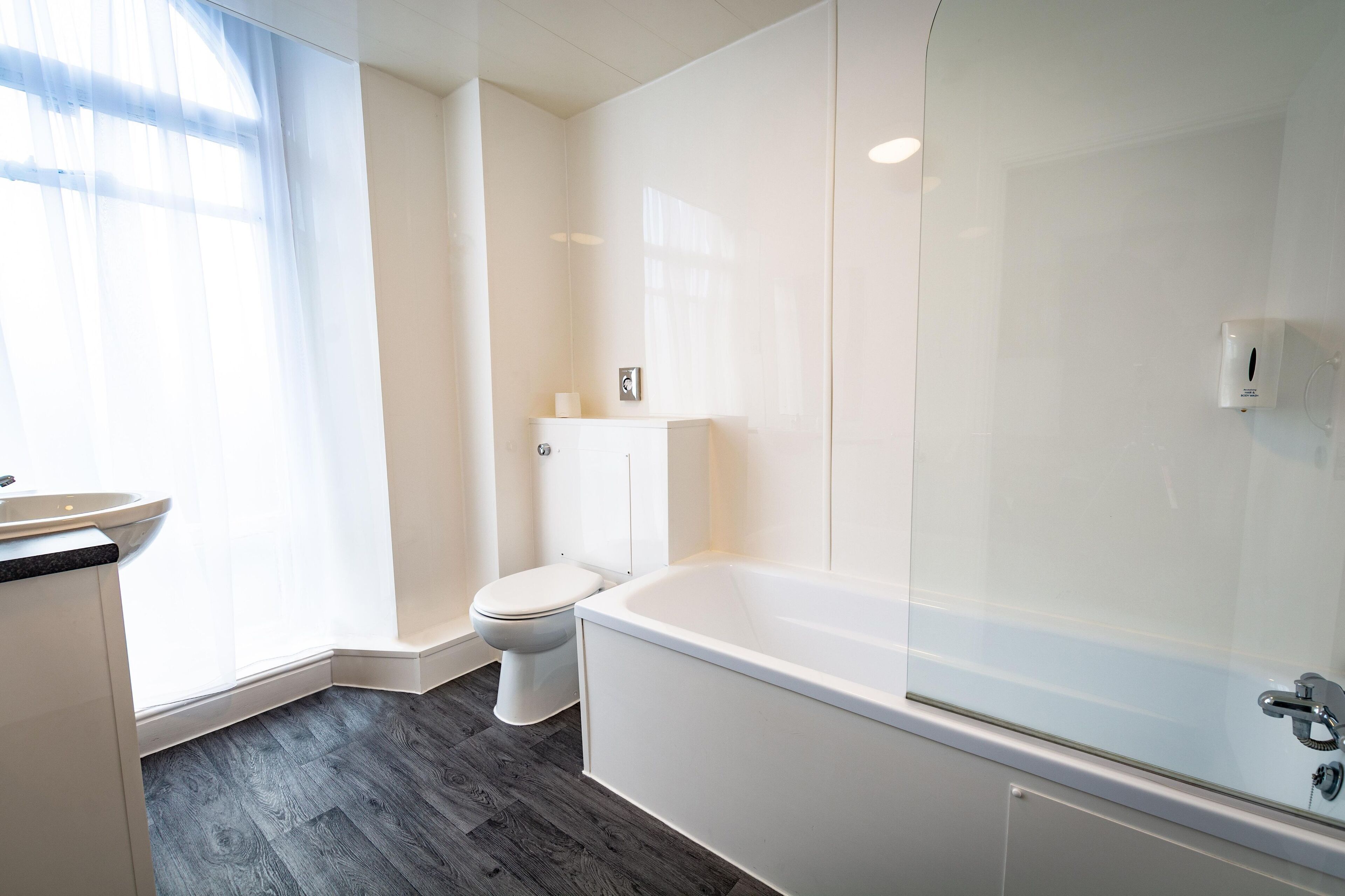 A modern bathroom with a toilet, bathtub, and sink.