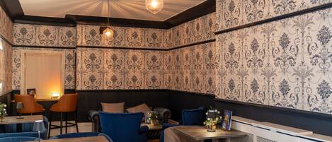 Ein Restaurantinnenraum mit strukturiertem Wandpapier, blau gepolsterten Stühlen und einem Holztisch.