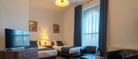 Une chambre d’hôtel avec deux lits, une télévision, un bureau, une chaise et une lampe.