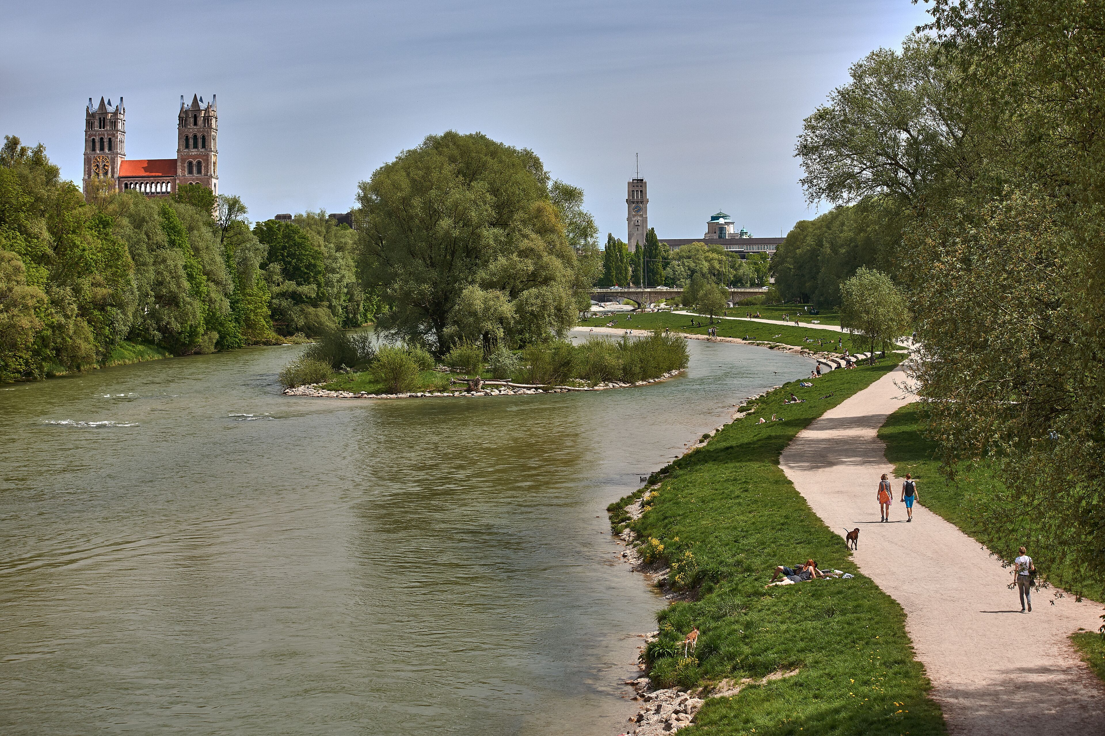 A riverside walkway with a historic building in the background.