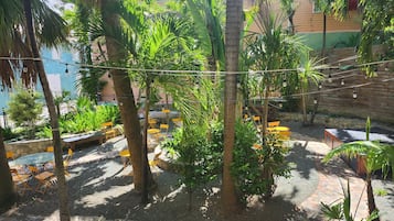 An outdoor seating area with tables and chairs, surrounded by palm trees and greenery.
