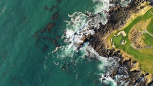 An aerial view of a coastal area with rocky terrain, a golf course, and a body of water. - Holiday Inn Express at Monterey Bay by IHG (Seaside)