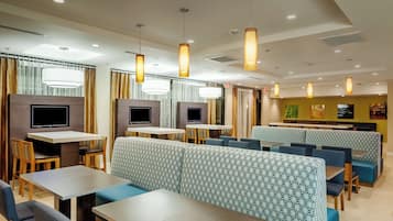 A modern restaurant interior with high tables, booths, and hanging pendant lights.