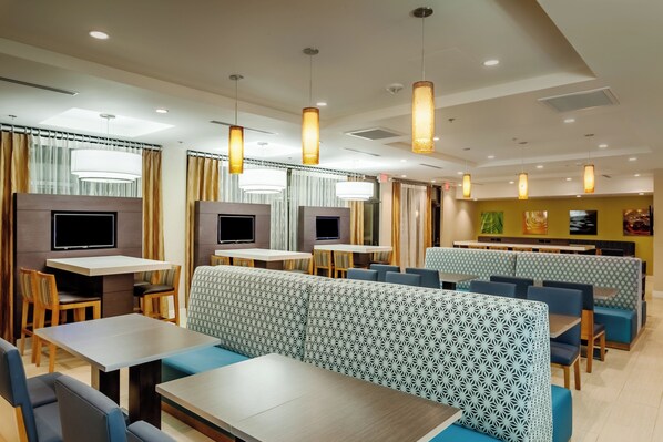 A modern restaurant interior with high tables, booths, and hanging pendant lights. - Holiday Inn Express at Monterey Bay by IHG (Seaside)