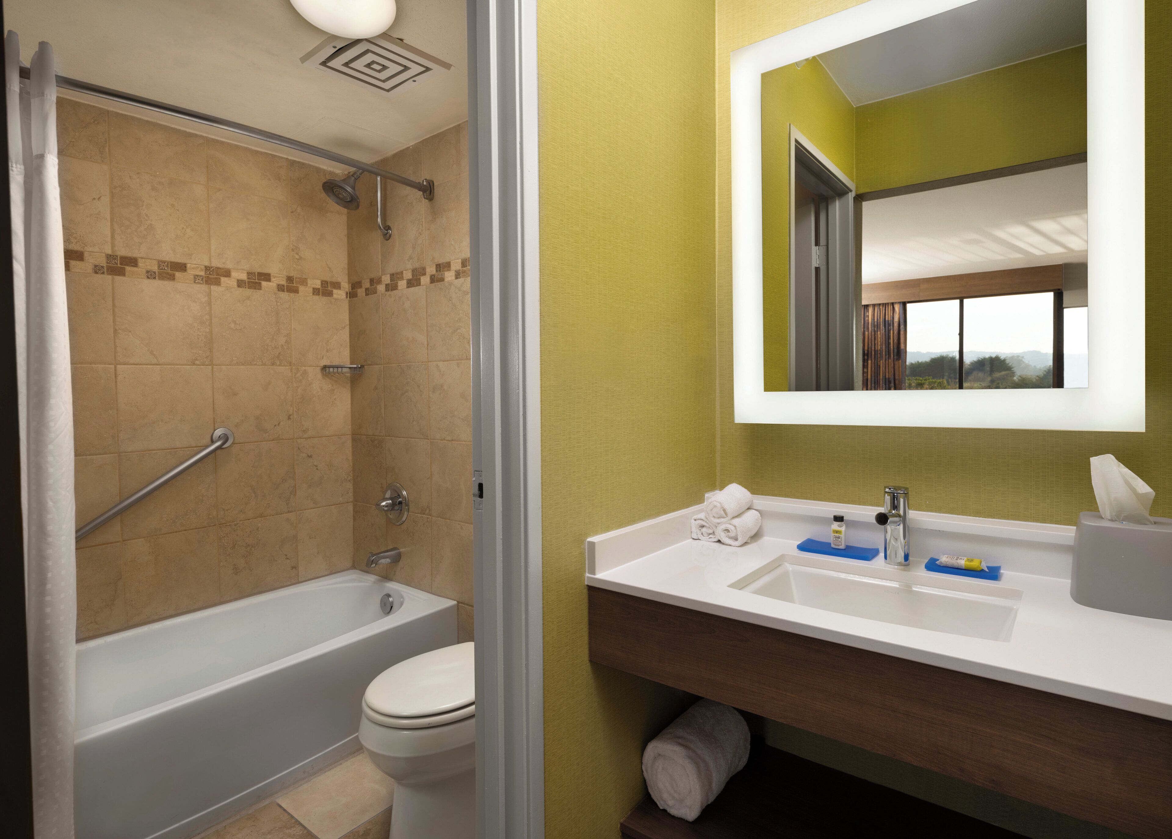 A bathroom with a bathtub, toilet, and a vanity with a mirror.