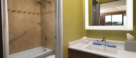 A bathroom with a bathtub, toilet, and a vanity with a mirror.